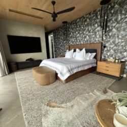Modern bedroom with timber ceiling, featuring bespoke upholstered headboard and premium textured carpeting.