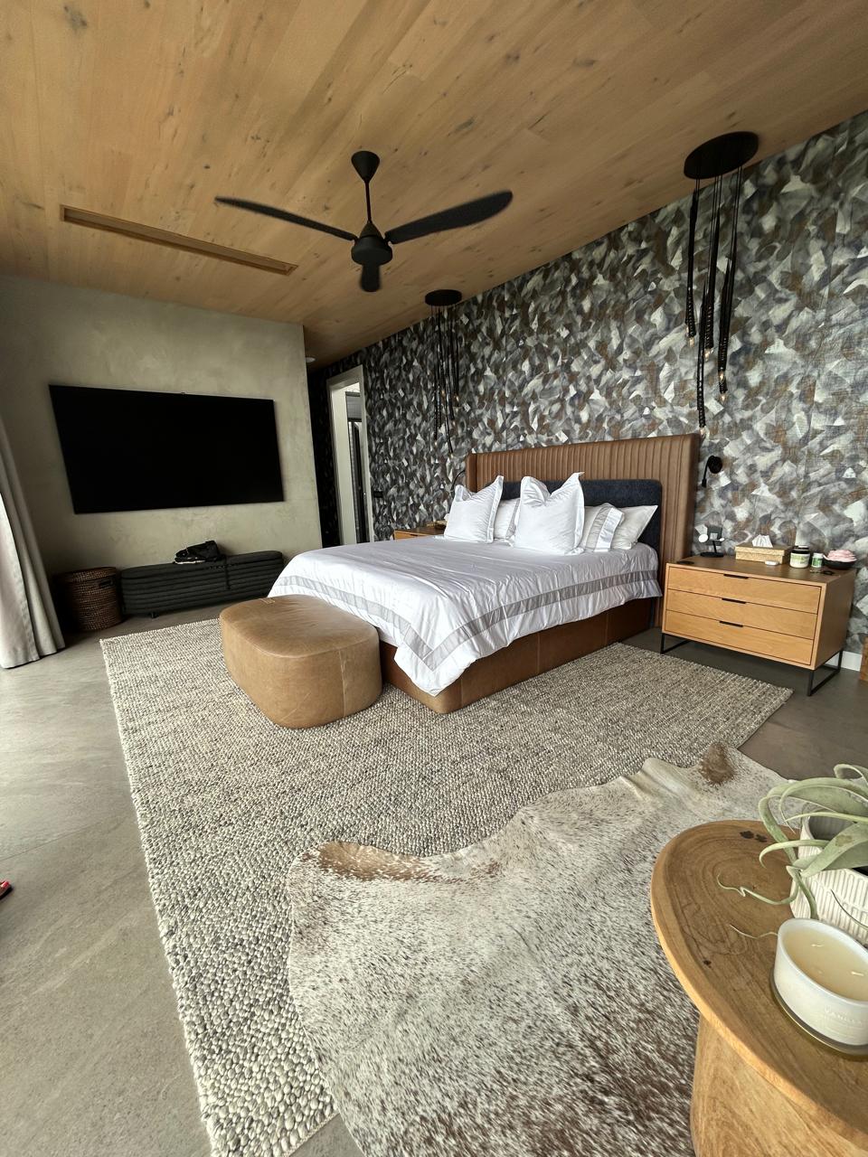 Modern bedroom with timber ceiling, featuring bespoke upholstered headboard and premium textured carpeting.