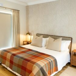 Coral Cove Zululami bedroom in Ballito with Arte wallpaper, upholstered headboard, curtains, boucle runners and bespoke bedside tables.