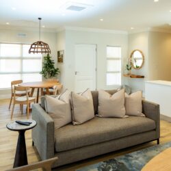Interior design living room with custom sofa, grey slate rug, round solid oak dining table and Iroko wood chandelier.