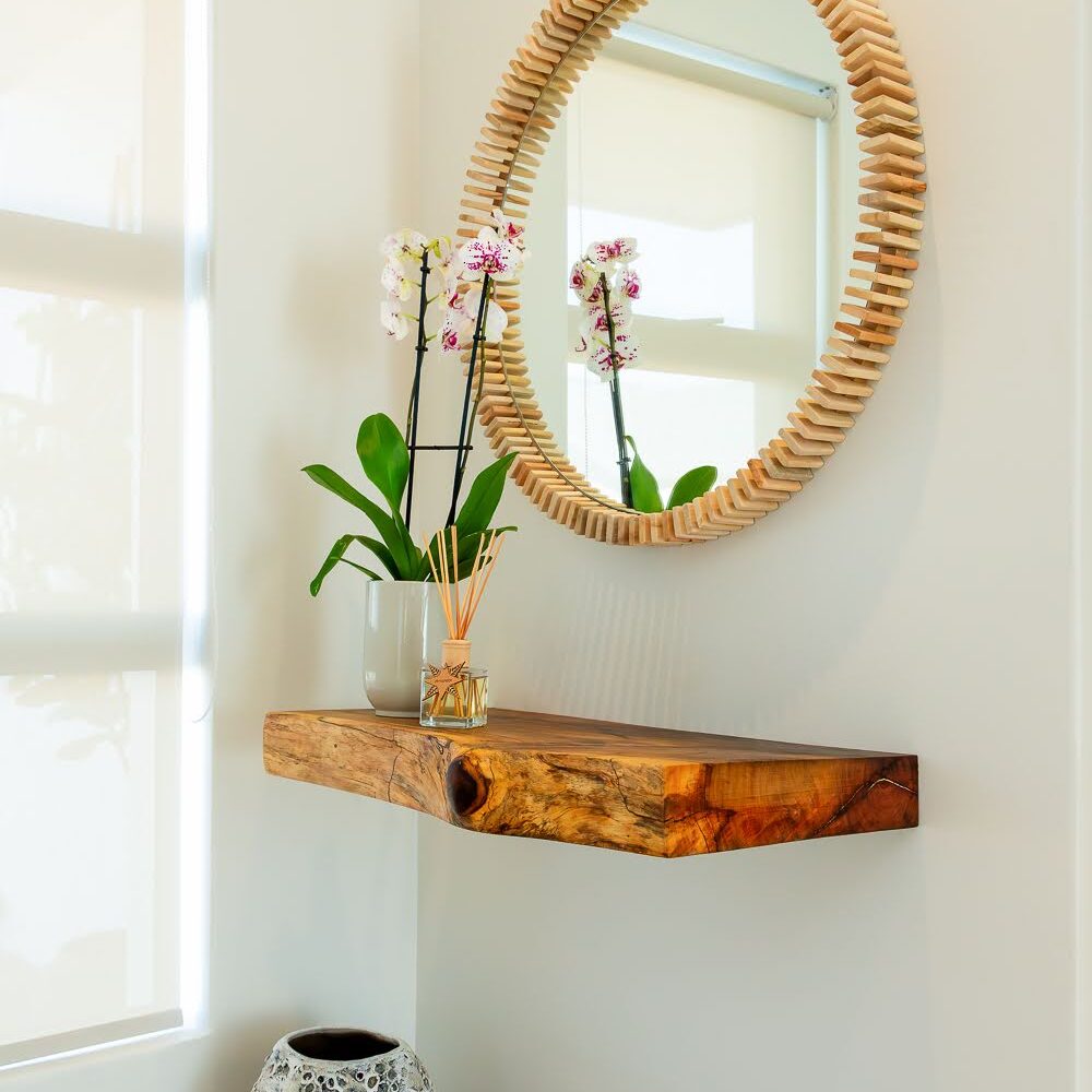 Interior design entrance with live-edge hardwood shelf, bespoke round wood mirror and lava pot.